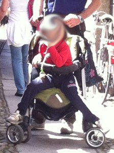 Un bambino italiano di 3-4 anni nel passeggino: la situazione è oltretutto ridicola perché non ci sta proprio!